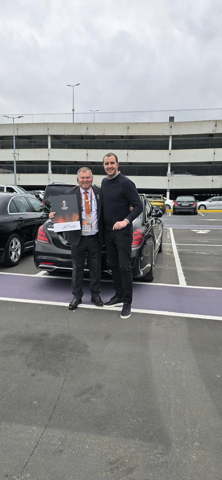 Alan McLoughlin, founder of Lir Executive Chauffeur Service, with a client beside a luxury sedan at Dublin Airport