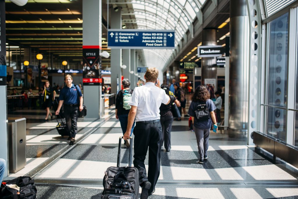 Travellers with luggage walking through a busy US airport terminal